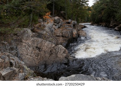 Dramatic rapids flowing past a rugged stone cliff in the parc des chutes dorwin