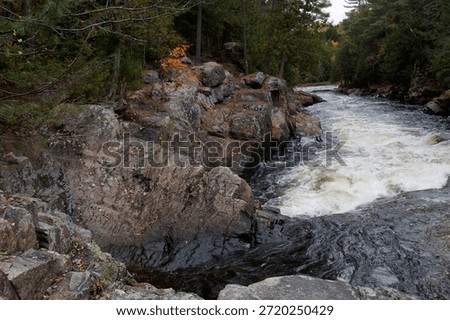 Dramatic rapids flowing past a rugged stone cliff in the parc des chutes dorwin