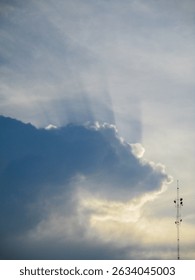 Dramatic rays of sunlight pierce through a dark cloud, creating a 