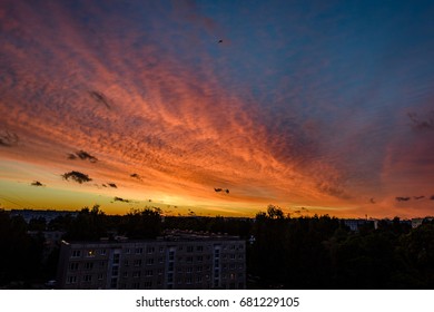 dramatic red and black clouds in sunset over city rooftops