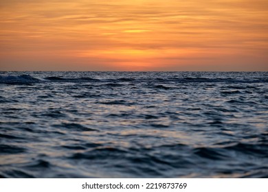 Dramatic red ocean waves at sunset with soft evening sea dark water
