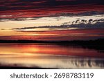 Dramatic red and orange sunset over Lac du Der with reflections on calm water, Champagne-Ardenne, France