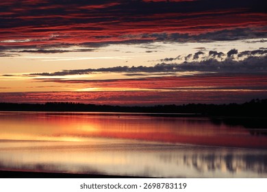 Dramatic red and orange sunset over Lac du Der with reflections on calm water, Champagne-Ardenne, France