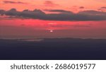 Dramatic red sunset over mountain silhouettes with glowing clouds in Norway.