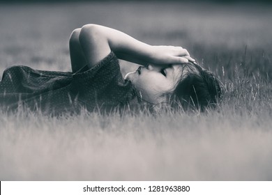 Dramatic Retro Black And White Image Of 6 Years Old Asian Girl Lie Down On The Yard Or Lawn In The Park. Child Covered Her Face With Hands,girl Look Sad,crying,in Trouble Or Scare.Concept Of Sad Kid. 