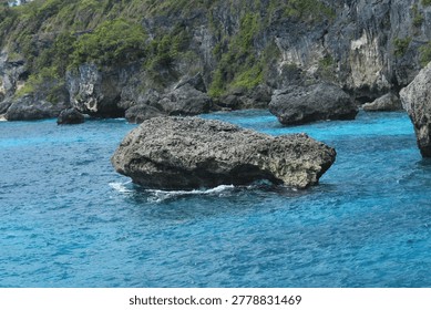 Dramatic rock formation in the middle of crystal clear turquoise sea