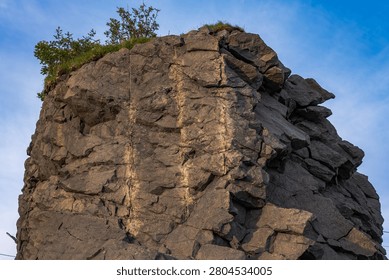 Dramatic rocky cliff face resembling an old man's profile in Lofoten, Norway. Weathered granite outcrop with sparse vegetation against