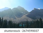 Dramatic rocky cliffs overlooking a vibrant alpine lake with calm turquoise waters in Banff National Park, Alberta, Canada.