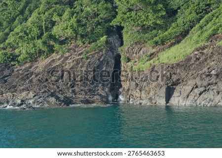 Dramatic rocky coastal cliffs with lush green jungle at a Thai island bay, Thailand.