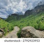 Dramatic rocky path leading to epic mountain cliffs under stormy sky, Czech Republic