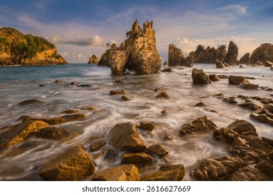 Dramatic rocky seascape at sunset with sharp cliffs, soft waves, and vibrant sky