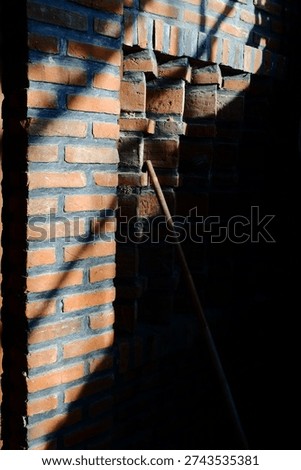 Dramatic rustic brick archway with wooden stick and contrasting shadows