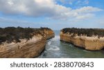 Dramatic sandstone cliffs frame a narrow ocean inlet at Loch Ard Gorge in Australia.