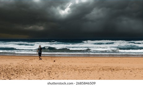 A dramatic scene at Praia do Telheiro in Portugal shows a lone woman walking toward a stormy Atlantic Ocean. 
