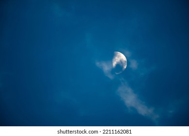 A dramatic scenery of the Moon behind the clouds in the blue sky at nigh