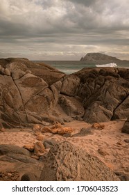 Dramatic Scenery With Rough Water Smashing Rocks With An Isolated Island In The Background. This Takes Place In A Remote Area In Western Australia