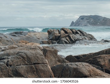 Dramatic Scenery With Rough Water Smashing Rocks With An Isolated Island In The Background. This Takes Place In A Remote Area In Western Australia