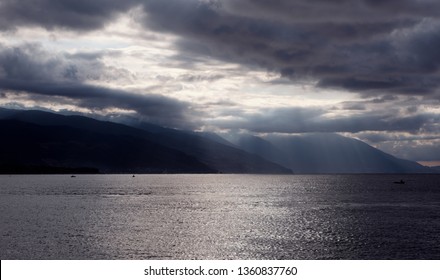 Dramatic sea view with sun breaking through dark clouds. Dark sea scape.