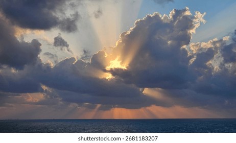 Dramatic seascape with clouds and sunlight breaking through, creating a crepuscular light effect.