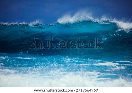 Dramatic seascape featuring powerful ocean waves crashing against rugged rocks and a rocky coastline. White foam and water splashes explode upon impact, creating a dynamic and awe-inspiring scene. The rough sea under a moody sky captures the raw energy and untamed beauty of nature. Perfect for themes of power, force, nature's fury, coastal erosion, and the majesty of the ocean. Ideal for backgrounds, wallpapers, travel, and adventure concepts.