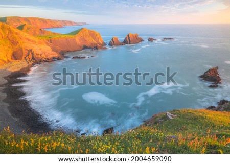 Dramatic seascape landscape of rock formations with golden hour sunset or sunrise light of Screda Point at Hartland Quay on the North Devon coast in England, UK.