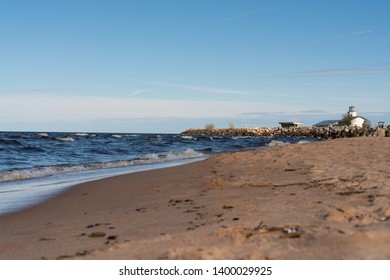 dramatic seascape waves on the Baltic sea with sandy beach and stone breakwater in the background