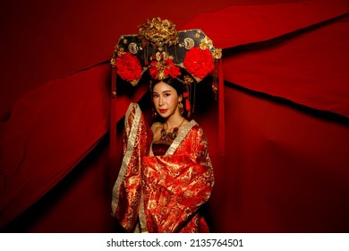 Dramatic Series Female Express Feeling Emotional With Fabric Fluttering In The Air. Asian Woman Wear China Royal Empress Traditional Costume With Golden Line Design Dress And Headwear, Red Background