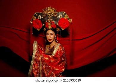 Dramatic Series Female Express Feeling Emotional With Fabric Fluttering In The Air. Asian Woman Wear China Royal Empress Traditional Costume With Golden Line Design Dress And Headwear, Red Background