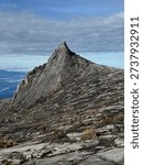 Dramatic sharp mountain peak with rugged granite rock formation under a cloudy sky. Scenic high-altitude landscape featuring textured stone slopes and natural wilderness terrain, symbolizing adventure, exploration, and remote nature beauty.