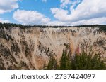 Dramatic sheer cliffs and eroded geological layers of the Grand Canyon of the Yellowstone under a blue sky, Yellowstone National Park, Wyoming, USA