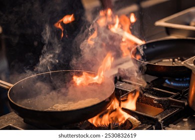 A dramatic shot of flames rising from a pan on a stovetop, indicating intense cooking action. The fiery scene suggests high-heat cooking, possibly sautéing or flambéing, creating a striking effect- - Powered by Shutterstock