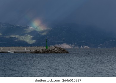 Dramatic sky after a storm, clouds over the Velebit Mountains in Croatia, a colorful rainbow breaks through the dark rain clouds