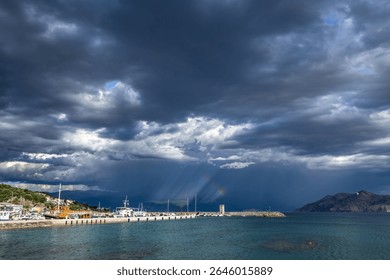 Dramatic sky after a storm, clouds over the Velebit Mountains in Croatia, a colorful rainbow breaks through the dark rain clouds