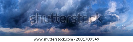 Dramatic sky background with dark rainy clouds at sunset.