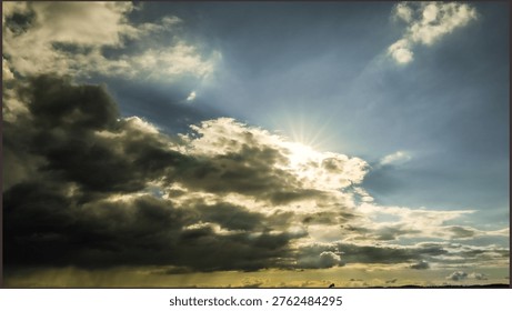 Dramatic sky with bright sun rays breaking through dark storm clouds. Beautiful celestial landscape showing light and shadow contrast during a dynamic weather change at sunset or sunrise.