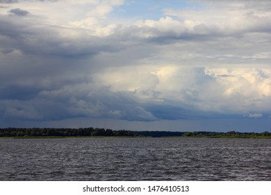 Dramatic sky clouds over lake, river stormy landscape