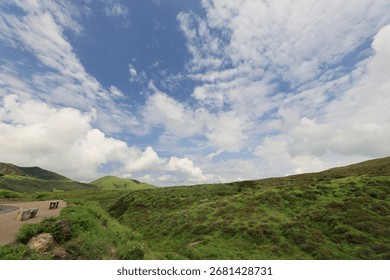 Dramatic sky with clouds over rolling green hills landscape.