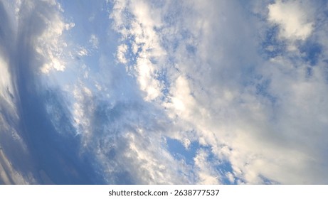 Dramatic Sky with Clouds. A scenic view of the sky filled with a dynamic arrangement of white and gray clouds against a soft blue backdrop.