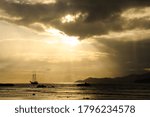 
Dramatic sky with clouds and sunbeam over the Indian Ocean with sailing boat during sunset.
