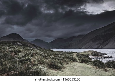 Dramatic Sky With Dark Clouds Over Scenic Mountain Valley With Lake In Lake District, England. Lakeshore Covered With Ferns.Low Key Image Of Majestic Landscape Of Rural Britain.Atmospheric Mood.