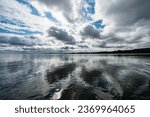 Dramatic sky with dark clouds reflecting off the calm sea, Edinburgh, Scotland.