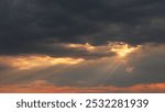 Dramatic sky with dark clouds and sun rays breaking through, creating a warm glow.