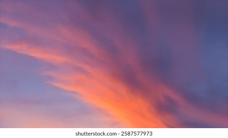 Dramatic sky with dark storm clouds contrasting with a vibrant, fiery sunrise glow at the horizon. Hints of pink and orange peek through.