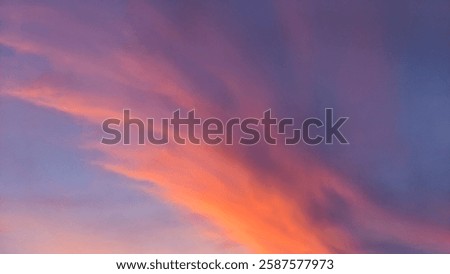 Dramatic sky with dark storm clouds contrasting with a vibrant, fiery sunrise glow at the horizon. Hints of pink and orange peek through.