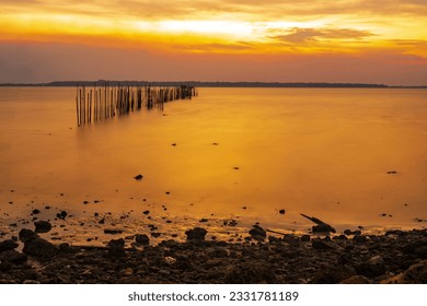 dramatic sky during sunset with rocks and boats foreground in Bangkalan, Madura, Indonesia.