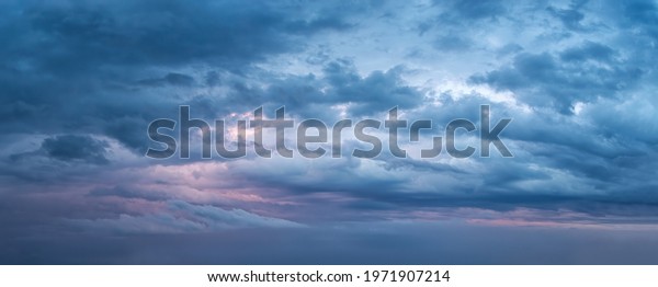 Dramatic sky at evening panoramic shot. Scenic blue\
gray clouds before the storm. Overcast cloudscape before the rain.\
Blue hour stormy cloudscape. Dark thunderstorm sky wide image. Sky\
only.