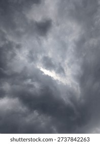 A dramatic sky filled with dark, heavy storm clouds, with a sliver of bright sunlight breaking through.