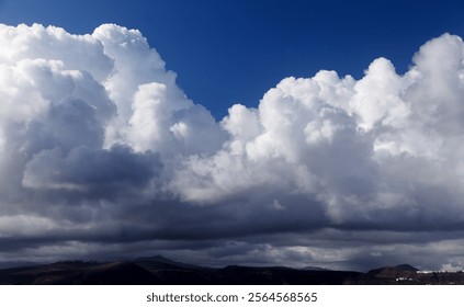 Dramatic sky with large cumulus clouds and dark blue sky over them
