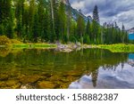 Dramatic Sky and mountain peaks reflection in Cascade Creek - Grand Tetons