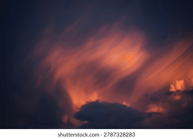 Dramatic sky with orange-lit wispy clouds at dusk, moody atmosphere